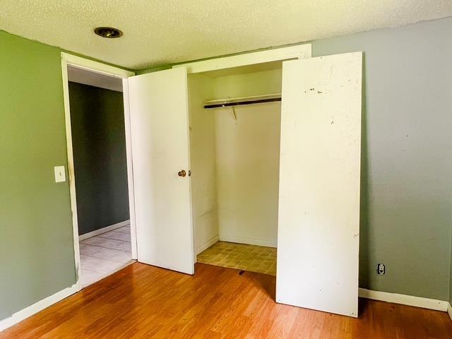 4815 Knollwood Dr, Harrison, MI 48625 - unfurnished bedroom with wood finished floors, a textured ceiling, and a closet