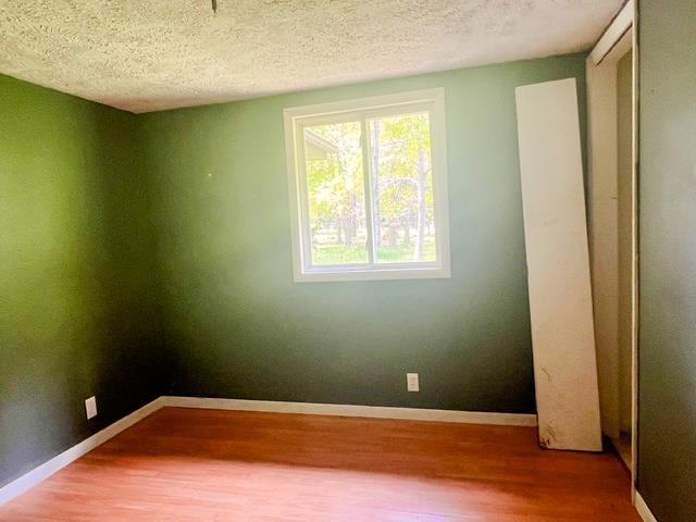 4815 Knollwood Dr, Harrison, MI 48625 - empty room featuring wood finished floors, a textured ceiling, and baseboards