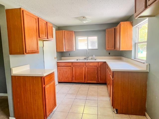 4815 Knollwood Dr, Harrison, MI 48625 - kitchen with a sink, a textured ceiling, light countertops, brown cabinets, and light tile patterned flooring