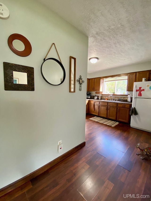 101-103 Juliet St, Marquette, MI 49855 - kitchen with freestanding refrigerator, brown cabinetry, dark wood-style floors, a textured ceiling, and baseboards