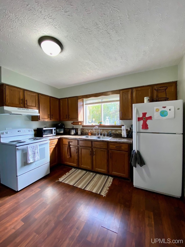 101-103 Juliet St, Marquette, MI 49855 - kitchen featuring white appliances, a sink, under cabinet range hood, dark wood-style floors, and brown cabinetry