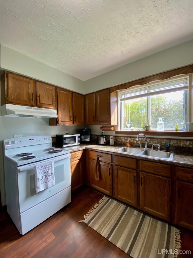 101-103 Juliet St, Marquette, MI 49855 - kitchen featuring white electric range, under cabinet range hood, a sink, dark wood-type flooring, and brown cabinetry