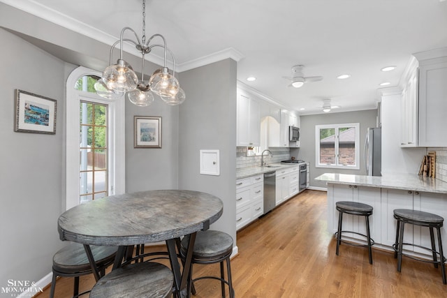 1264 Bedford Rd, Grosse Pointe Park, MI 48230 - kitchen featuring stainless steel appliances, white cabinetry, tasteful backsplash, a sink, and crown molding