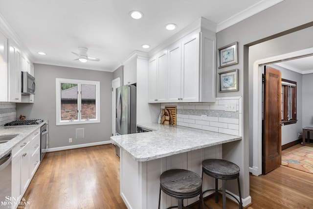 1264 Bedford Rd, Grosse Pointe Park, MI 48230 - kitchen featuring appliances with stainless steel finishes, white cabinets, crown molding, baseboards, and decorative backsplash