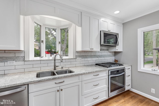 1264 Bedford Rd, Grosse Pointe Park, MI 48230 - kitchen with appliances with stainless steel finishes, a sink, white cabinetry, decorative backsplash, and plenty of natural light