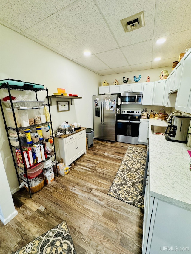 200 Marquette St, Negaunee, MI 49866 - kitchen with appliances with stainless steel finishes, a paneled ceiling, light wood finished floors, light countertops, and white cabinetry
