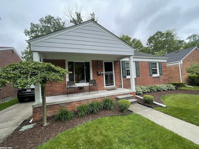 2029 Manchester Rd, Grosse Pointe Woods, MI 48236 - view of front facade with covered porch, brick siding, a front lawn, and driveway