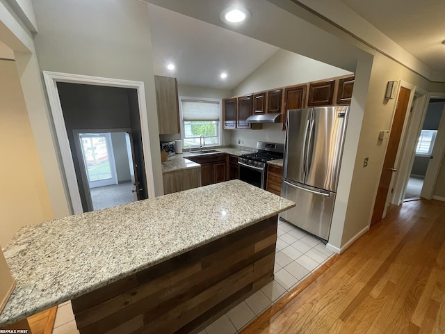2029 Manchester Rd, Grosse Pointe Woods, MI 48236 - kitchen featuring appliances with stainless steel finishes, under cabinet range hood, a sink, light stone countertops, and vaulted ceiling
