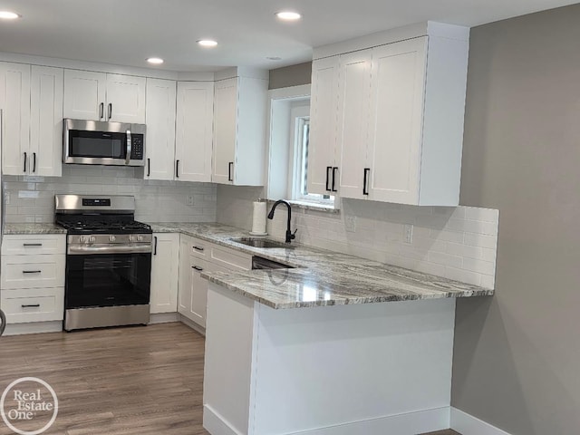 53340 Washington St, New Baltimore, MI 48047 - kitchen with appliances with stainless steel finishes, a sink, white cabinetry, a peninsula, and light stone countertops