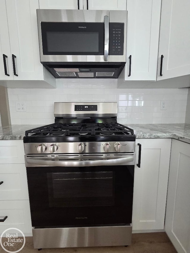 53340 Washington St, New Baltimore, MI 48047 - kitchen featuring appliances with stainless steel finishes, white cabinets, and light stone countertops