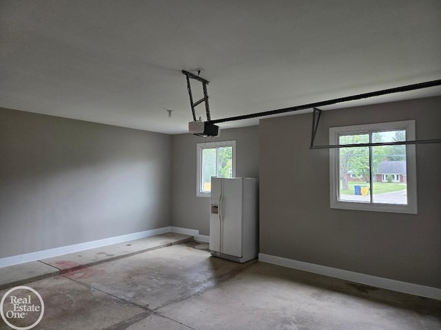 53340 Washington St, New Baltimore, MI 48047 - garage with white refrigerator with ice dispenser, a garage door opener, and baseboards