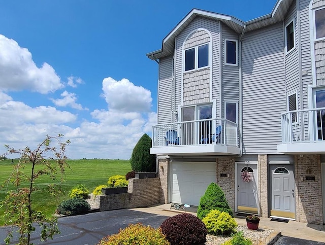 1750 Castleview Ct, Gladwin, MI 48624 - view of front of home featuring asphalt driveway, a balcony, brick siding, and a garage