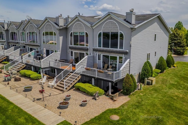 1750 Castleview Ct, Gladwin, MI 48624 - rear view of property with a chimney, a deck, stairway, and a yard