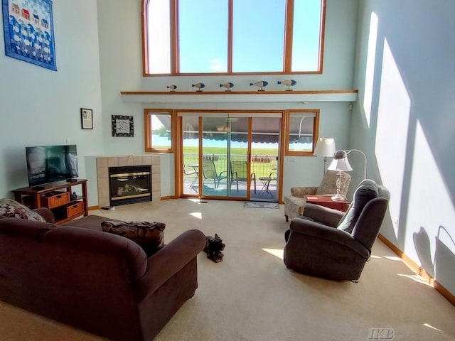 1750 Castleview Ct, Gladwin, MI 48624 - carpeted living area with a towering ceiling, a tiled fireplace, and baseboards