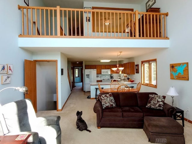 1750 Castleview Ct, Gladwin, MI 48624 - living room featuring light carpet, a towering ceiling, and baseboards