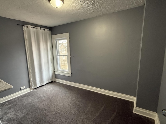 1009 May St, Lansing, MI 48906 - spare room featuring a textured ceiling, dark colored carpet, and baseboards