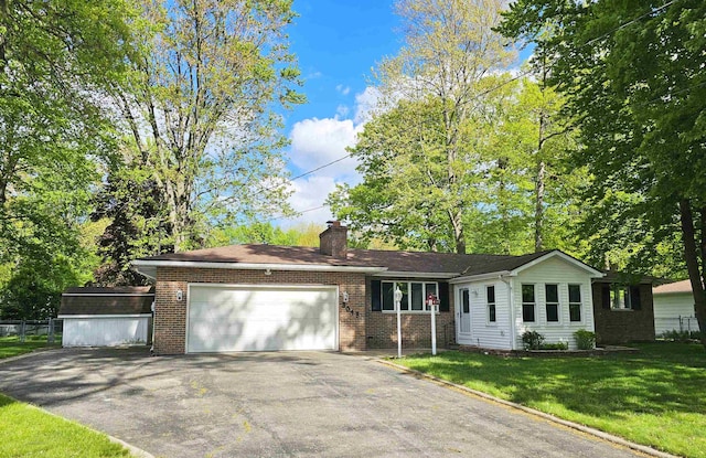 3045 W Birch Dr, Bay City, MI 48706 - single story home featuring asphalt driveway, an attached garage, a front lawn, a chimney, and brick siding