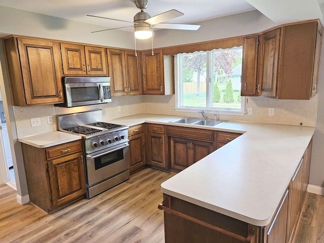 3045 W Birch Dr, Bay City, MI 48706 - kitchen with stainless steel appliances, a sink, light wood-style flooring, and brown cabinetry