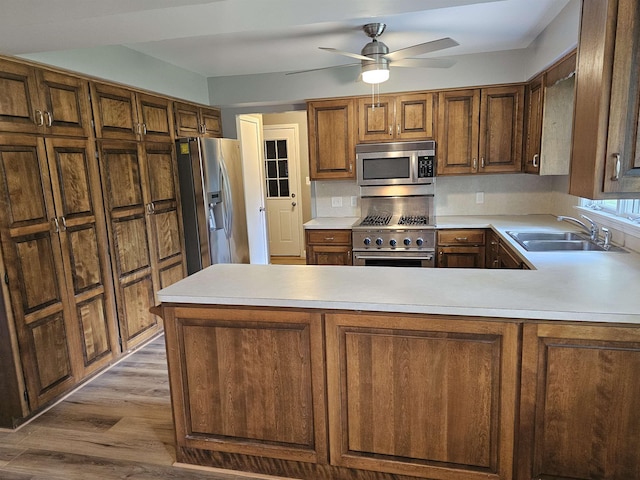 3045 W Birch Dr, Bay City, MI 48706 - kitchen featuring appliances with stainless steel finishes, a sink, light countertops, wood finished floors, and a peninsula