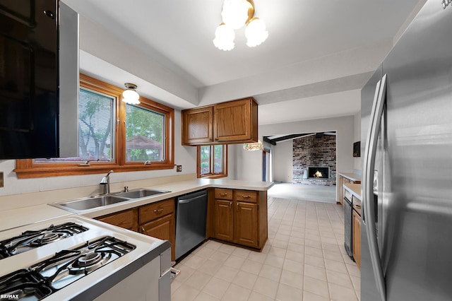 39067 Baroque Blvd, Clinton Township, MI 48038 - kitchen featuring appliances with stainless steel finishes, brown cabinets, light tile patterned flooring, a fireplace, and a peninsula