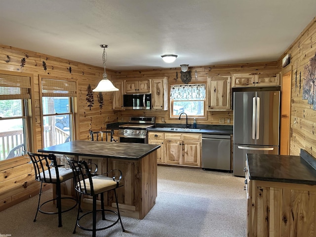 5077 Henry Hwy, Lewiston, MI 49756 - kitchen featuring appliances with stainless steel finishes, wood walls, light carpet, a sink, and pendant lighting