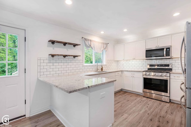 229 Mussey St, Romeo, MI 48065 - kitchen featuring appliances with stainless steel finishes, a peninsula, white cabinetry, light stone countertops, and a sink