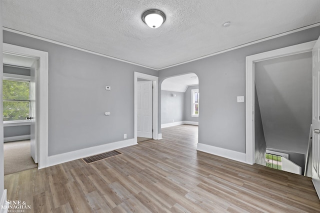 5553 Nottingham Rd, Detroit, MI 48224 - spare room with arched walkways, a textured ceiling, light wood-style floors, baseboards, and crown molding