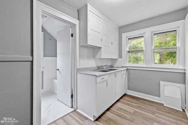 5553 Nottingham Rd, Detroit, MI 48224 - kitchen featuring a sink, white cabinetry, light wood finished floors, light countertops, and baseboards