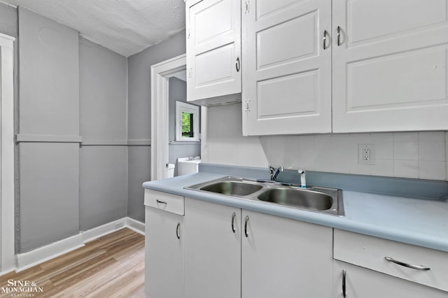 5553 Nottingham Rd, Detroit, MI 48224 - kitchen featuring a sink, backsplash, white cabinets, light wood-type flooring, and light countertops