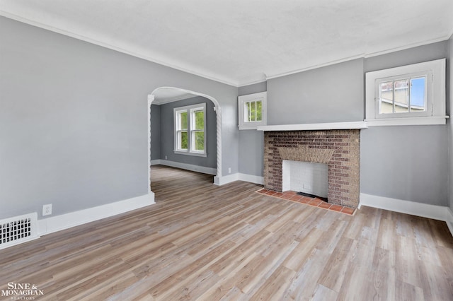 5553 Nottingham Rd, Detroit, MI 48224 - unfurnished living room featuring a brick fireplace, baseboards, arched walkways, crown molding, and wood finished floors