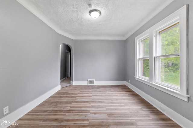 5553 Nottingham Rd, Detroit, MI 48224 - spare room featuring arched walkways, a textured ceiling, light wood-type flooring, and baseboards