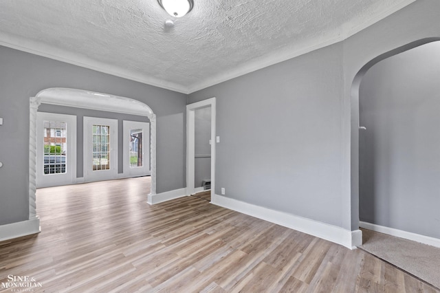 5553 Nottingham Rd, Detroit, MI 48224 - empty room featuring arched walkways, wood finished floors, a textured ceiling, baseboards, and ornamental molding