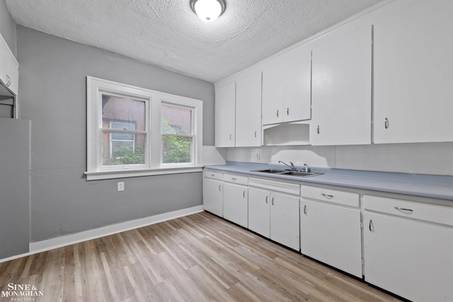5553 Nottingham Rd, Detroit, MI 48224 - kitchen with a sink, light wood-style floors, light countertops, white cabinets, and decorative backsplash