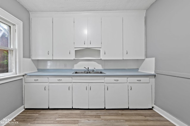 5553 Nottingham Rd, Detroit, MI 48224 - kitchen featuring a sink, light countertops, white cabinets, light wood finished floors, and baseboards