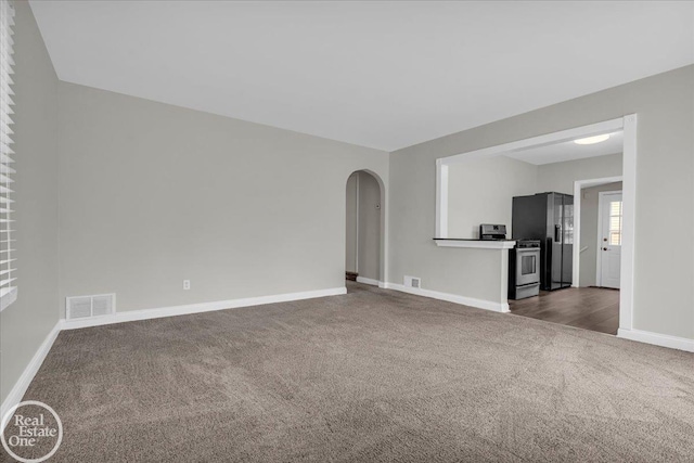 1011 Garfield St, Port Huron, MI 48060 - unfurnished living room featuring dark colored carpet, baseboards, and arched walkways