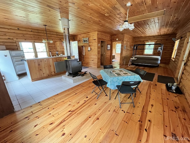 14520 7th Rd, Garden, MI 49835 - dining space featuring a wood stove, rustic walls, wood ceiling, light wood-style flooring, and plenty of natural light