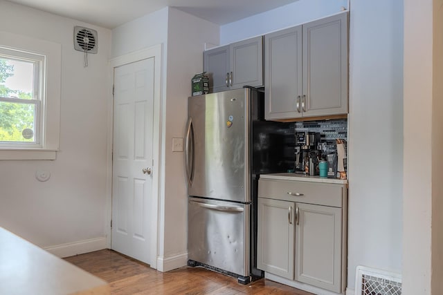 2129 N Clinton St, Saginaw, MI 48602 - kitchen with freestanding refrigerator, gray cabinets, light wood-style flooring, backsplash, and baseboards