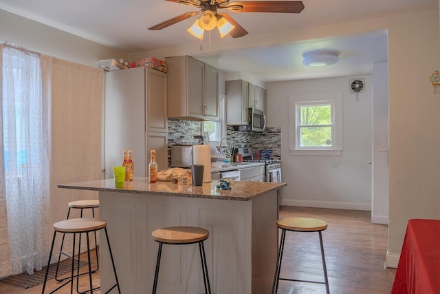 2129 N Clinton St, Saginaw, MI 48602 - kitchen with appliances with stainless steel finishes, a breakfast bar, gray cabinetry, a ceiling fan, and baseboards