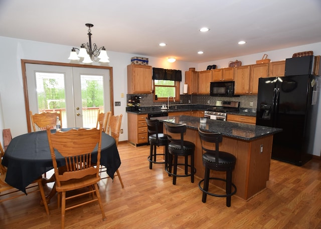 3850 Mando Ct, Coleman, MI 48611 - kitchen with black appliances, a sink, a chandelier, a center island, and backsplash