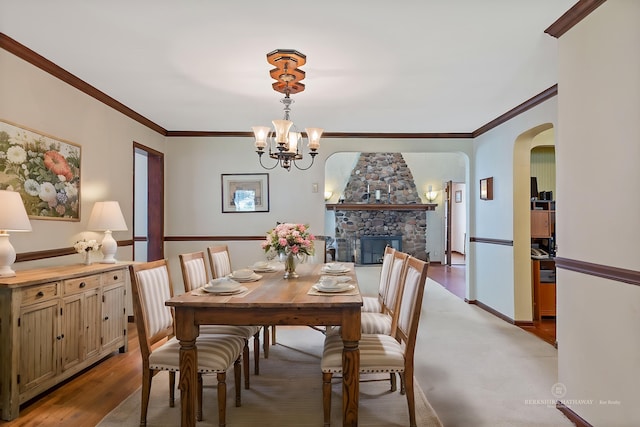48816 Point Lakeview Dr, Chesterfield Twp, MI 48047 - dining area featuring a chandelier, arched walkways, a stone fireplace, light wood-style floors, and ornamental molding