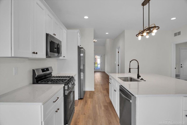 27645 Maryjane Ln E, Chesterfield Twp, MI 48047 - kitchen with appliances with stainless steel finishes, a sink, light wood-style floors, a center island with sink, and white cabinets