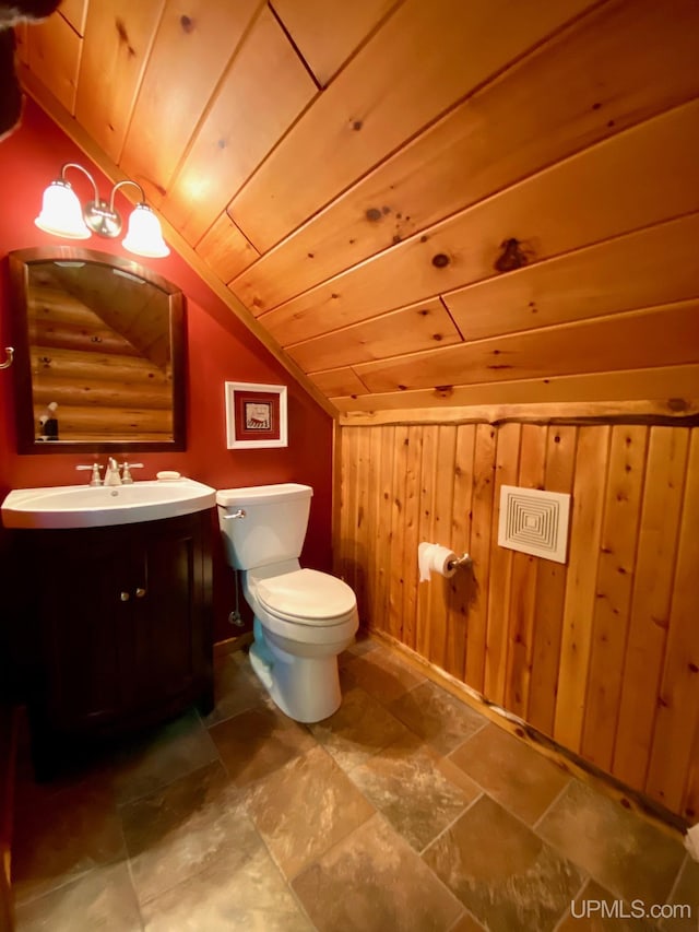 E1849 H44 Hwy, Trenary, MI 49891 - bathroom with vaulted ceiling, toilet, vanity, wooden walls, and stone finish flooring
