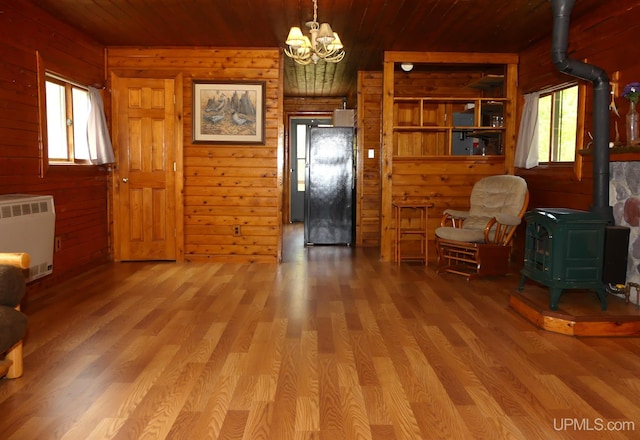 22252 E Webb Rd, Grand Marais, MI 49839 - living area featuring a wood stove, radiator heating unit, a chandelier, wooden walls, and wooden ceiling