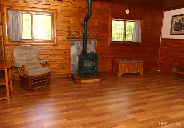 22252 E Webb Rd, Grand Marais, MI 49839 - living room featuring a wood stove, light wood-type flooring, and wooden walls