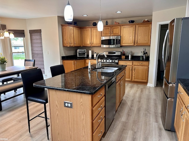 39148 Canterbury Dr, Harrison Twp, MI 48045 - kitchen with appliances with stainless steel finishes, a sink, a breakfast bar area, light wood-style floors, and a kitchen island with sink