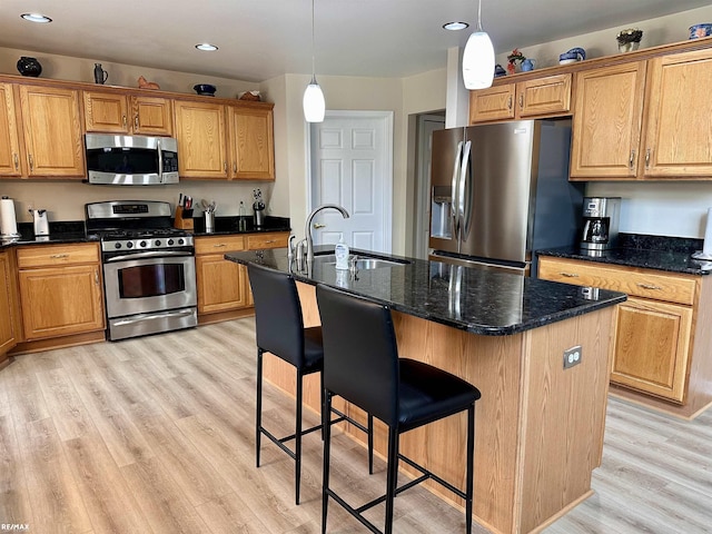39148 Canterbury Dr, Harrison Twp, MI 48045 - kitchen featuring appliances with stainless steel finishes, a sink, light wood-style flooring, a breakfast bar area, and a kitchen island with sink