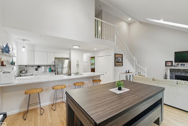 3620 Lakeshore Dr, Lapeer, MI 48446 - dining area with light wood-type flooring, high vaulted ceiling, stairway, a high end fireplace, and recessed lighting