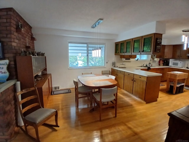22460 La Von St, Saint Clair Shores, MI 48081 - kitchen featuring a peninsula, light wood-style flooring, white microwave, light countertops, and brown cabinetry