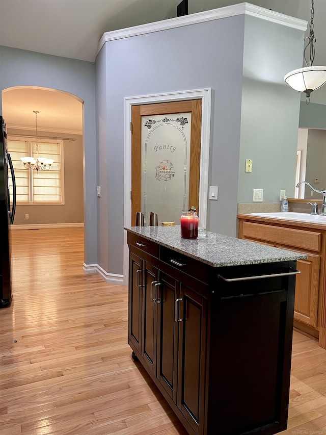 815 Cove Rd, Wales, MI 48027 - bar featuring light wood-type flooring, freestanding refrigerator, a sink, arched walkways, and hanging light fixtures