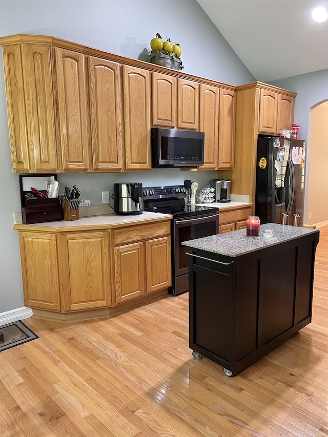 815 Cove Rd, Wales, MI 48027 - kitchen with stainless steel range with electric stovetop, black refrigerator with ice dispenser, light wood finished floors, lofted ceiling, and arched walkways